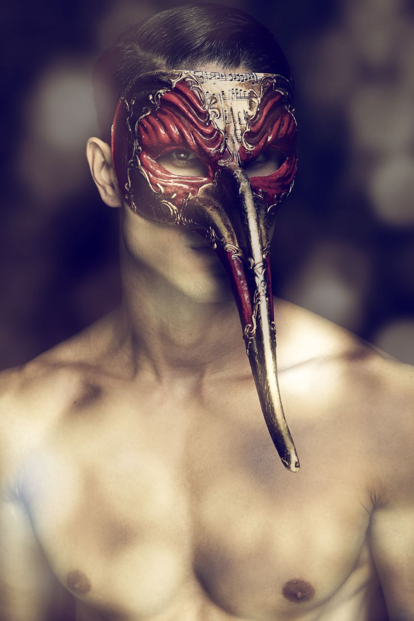 A man in a red and gold Venetian mask with a long beak